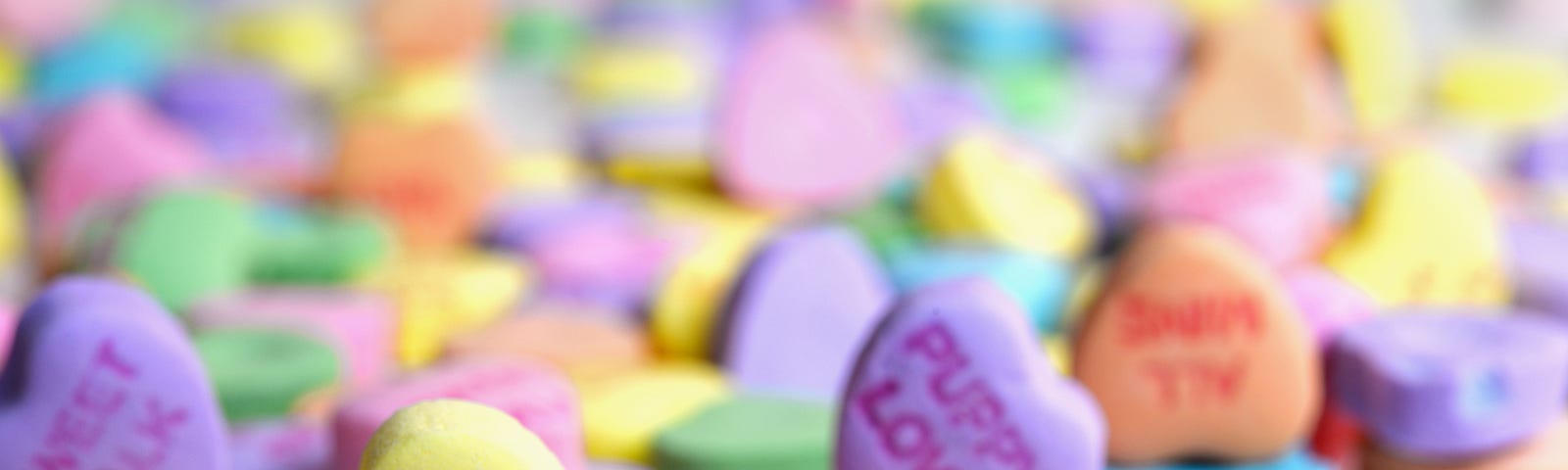 Photo of candy hearts, all different colors. Messages say “true love,” “say yes,” “first kiss.” by Laura Ockel