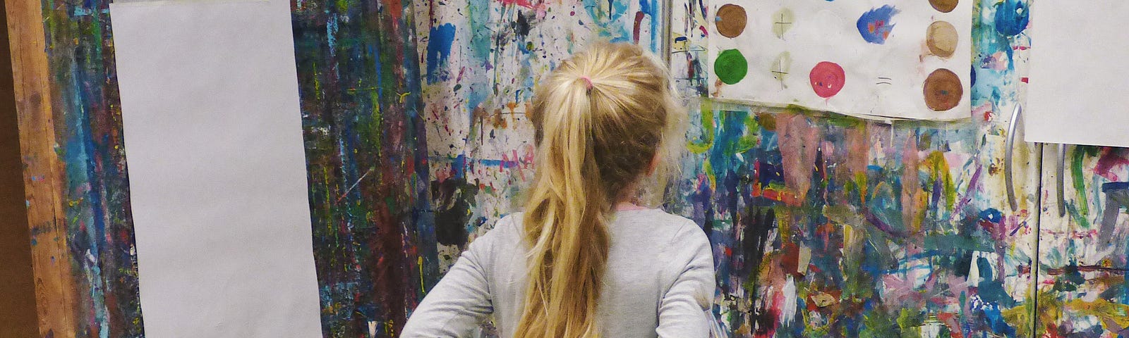 A young girl looking at a painted wall.