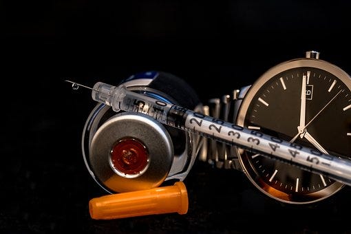 An image if insulin, syringe and a watch depicting that insulin should be taken timely to manage your blood sugar levels and to keep them in normal range.