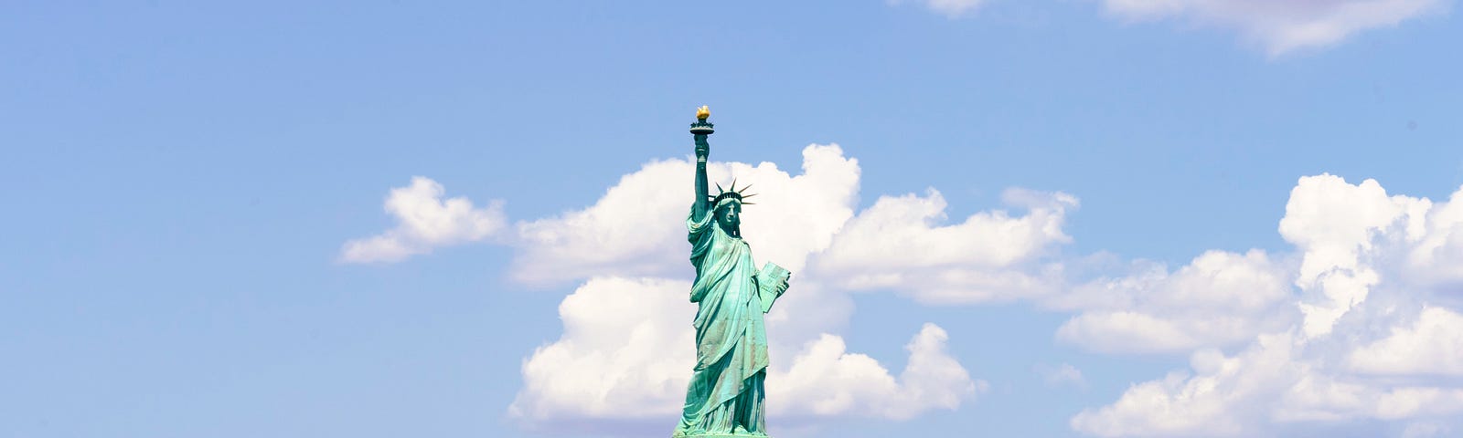 The Statue of Liberty against a cloud-dotted sky