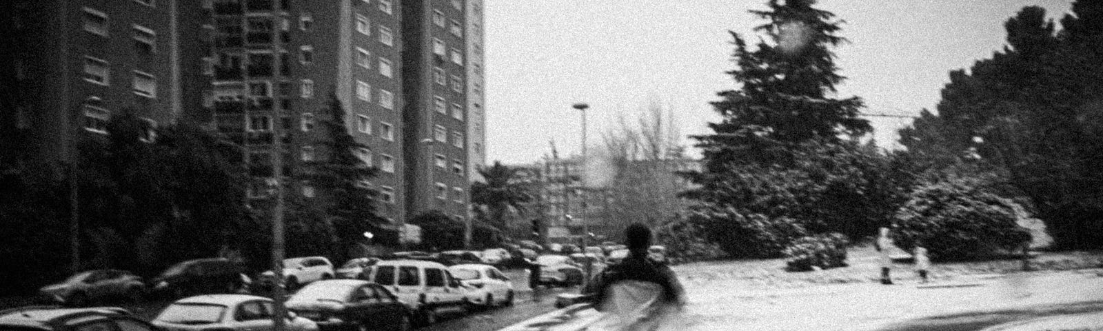 Teen boy in shorts running away from camera, down inner city street.