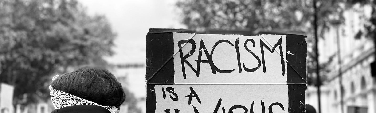 woman carrying sign that says: Racism is a Virus