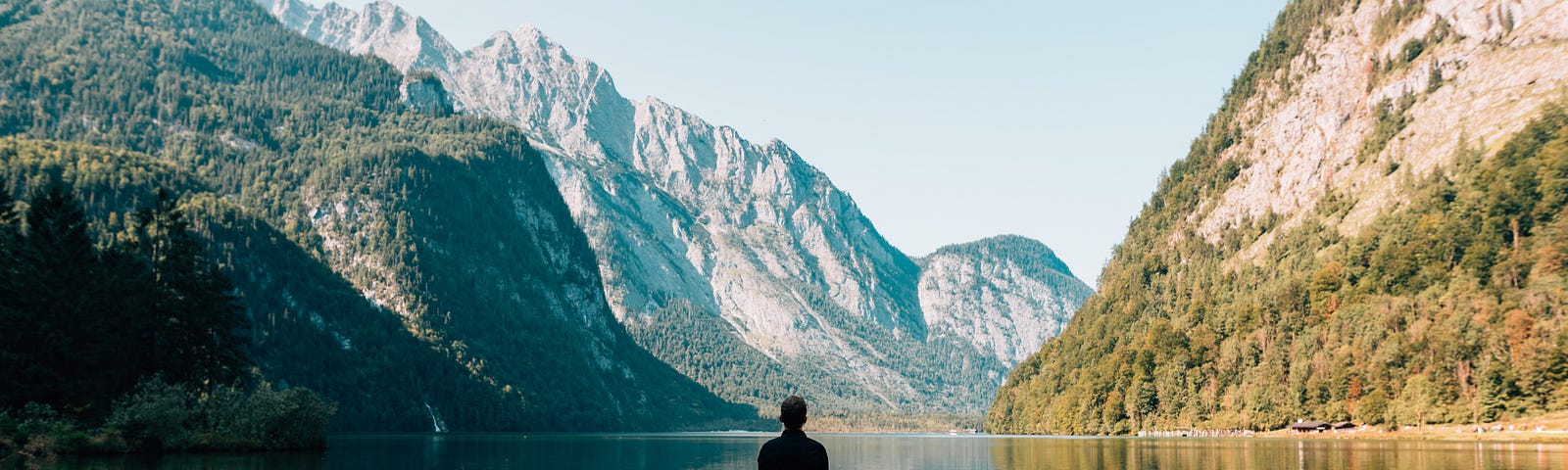 person sitting on a dock overlooking the lake and mountains