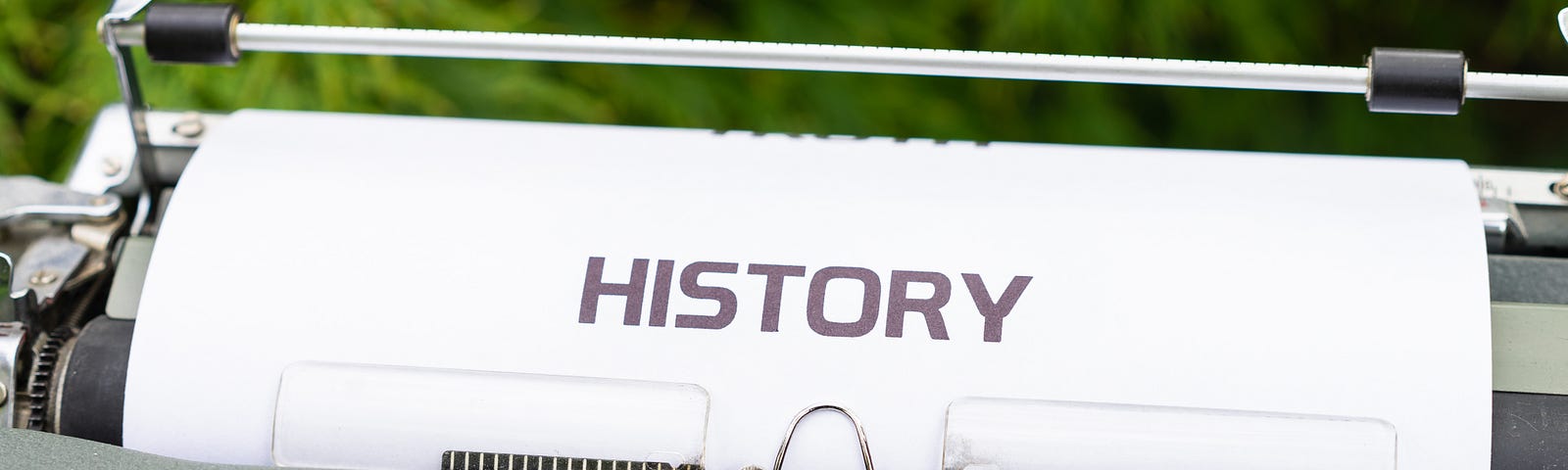 An antique typewriter holds a sheet of paper entitled History