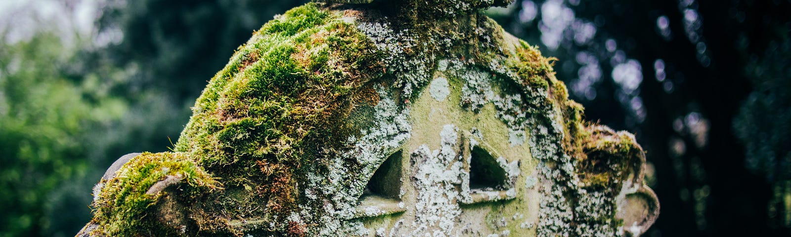 gravestone that is a Celtic cross, covered in moss