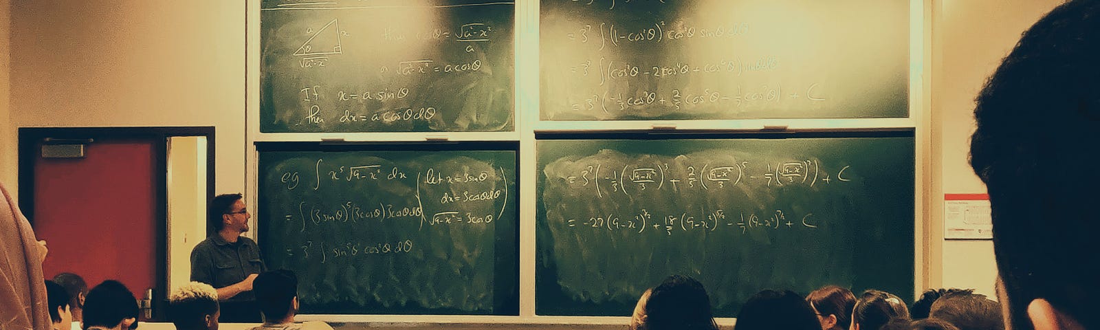 Students sit in a class with algebra on the chalkboard