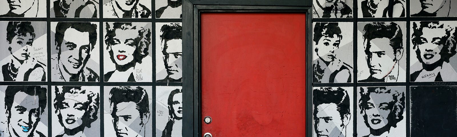 A wall full of black and white photos of actors with a red door in the middle.