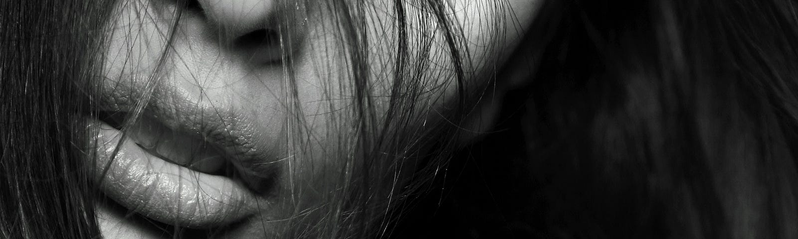 Black and white photography of a woman’s face covered slightly by her hair