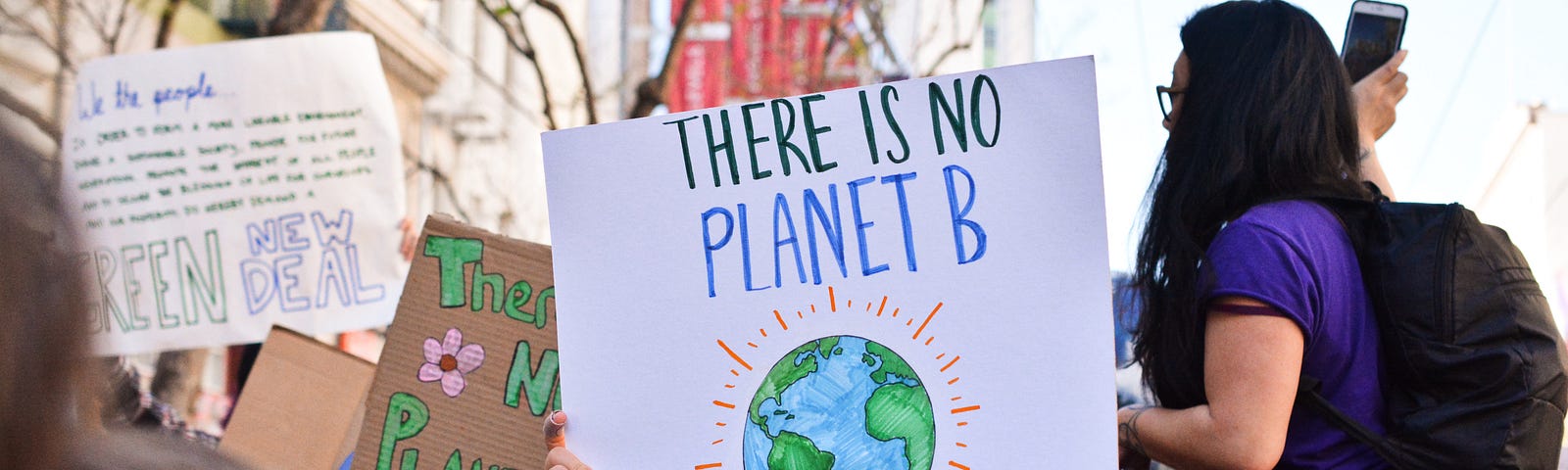People protesting climate change with sign that reads, “There is no Planet B”