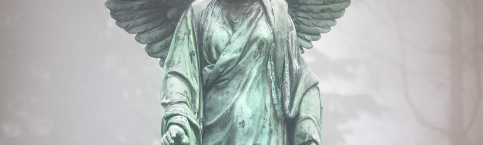 A tall female angel, as a green stone statue, looking down to its pedestal.