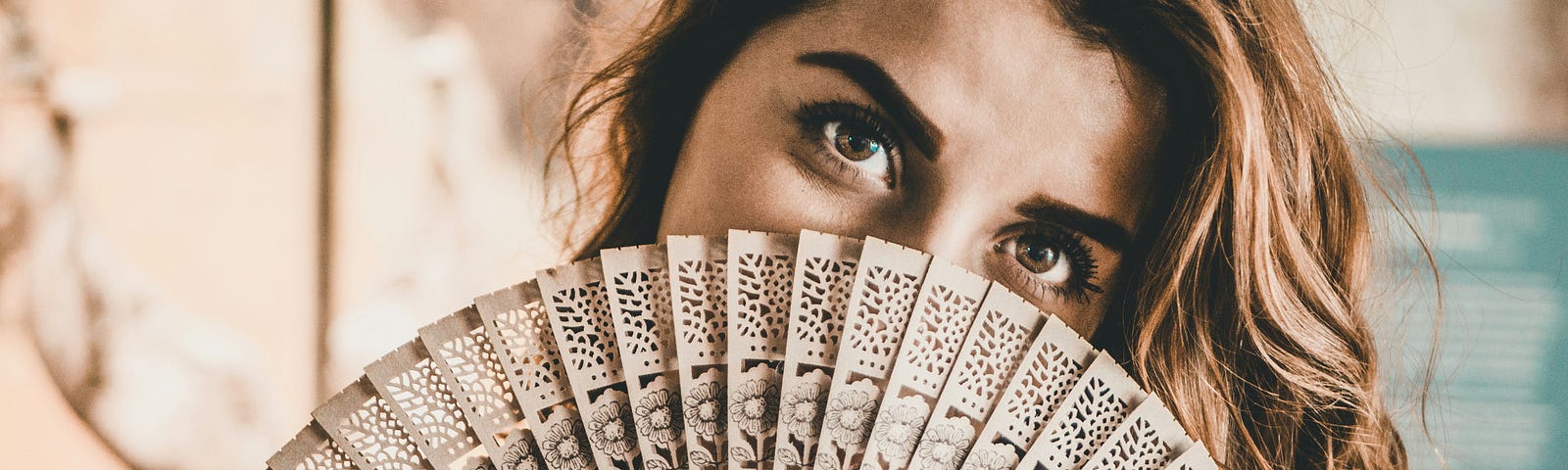 A woman with a fan partially covering her face, long hair