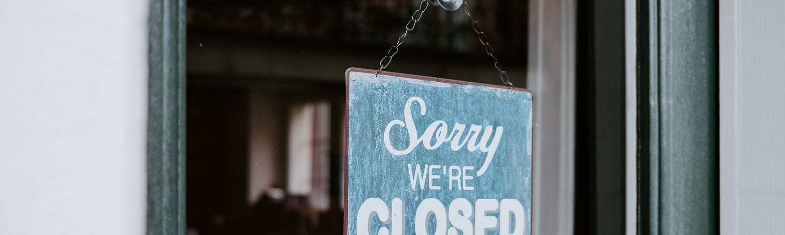 A sign in a shop window that says “sorry, we’re closed”