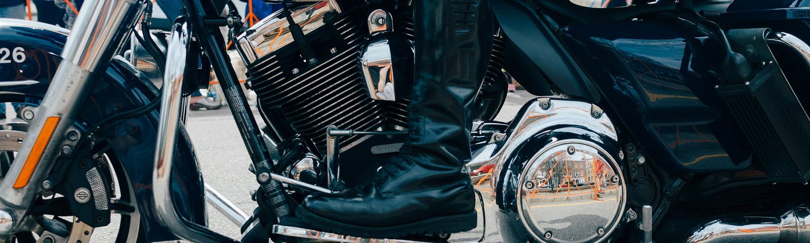 Close up of a polished police motorcycle. The camera focuses on the driver’s boots, which are equally polished to a shine.