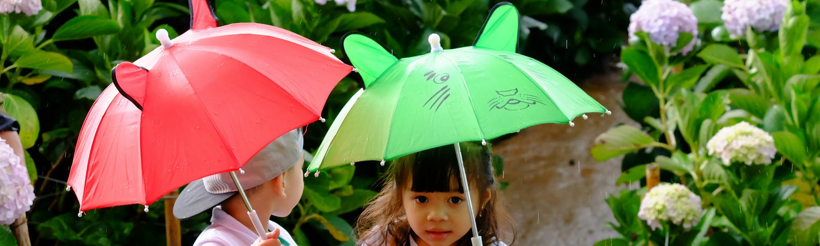 Children with umbrellas in a garden.