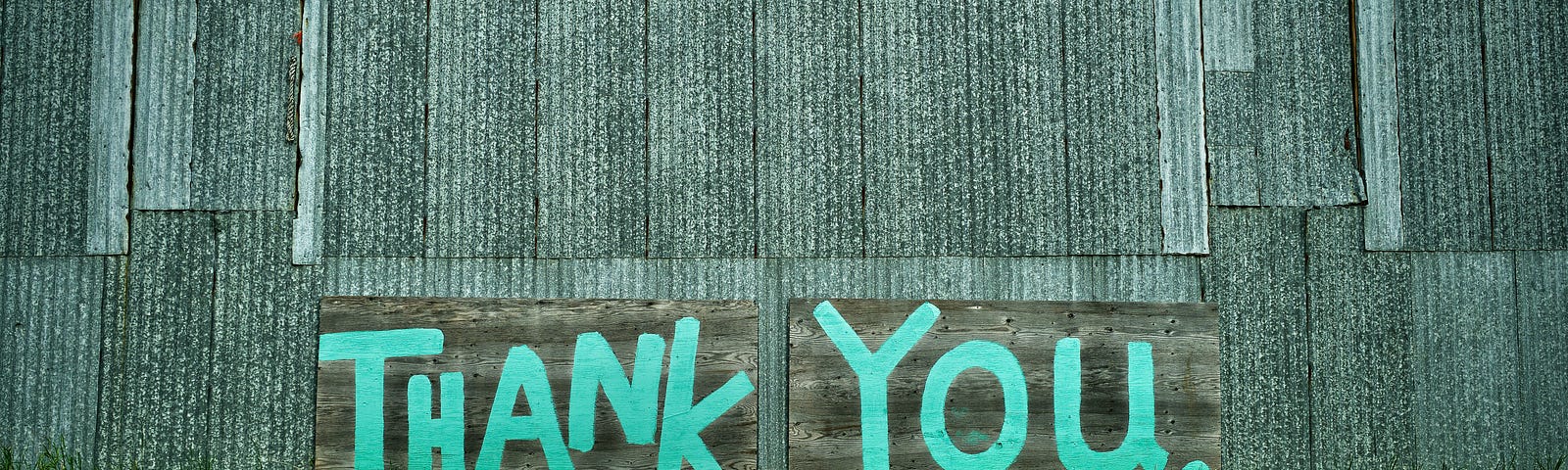 Painted blue thank you on a grey barn wall