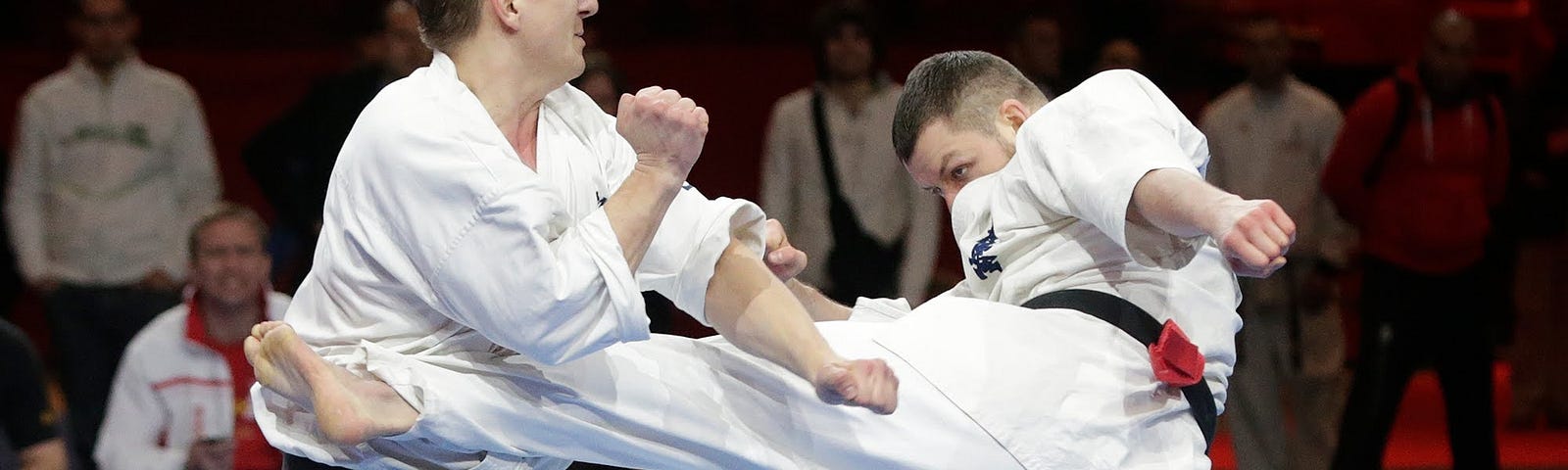 A Karateka performs a kick against an opponent.