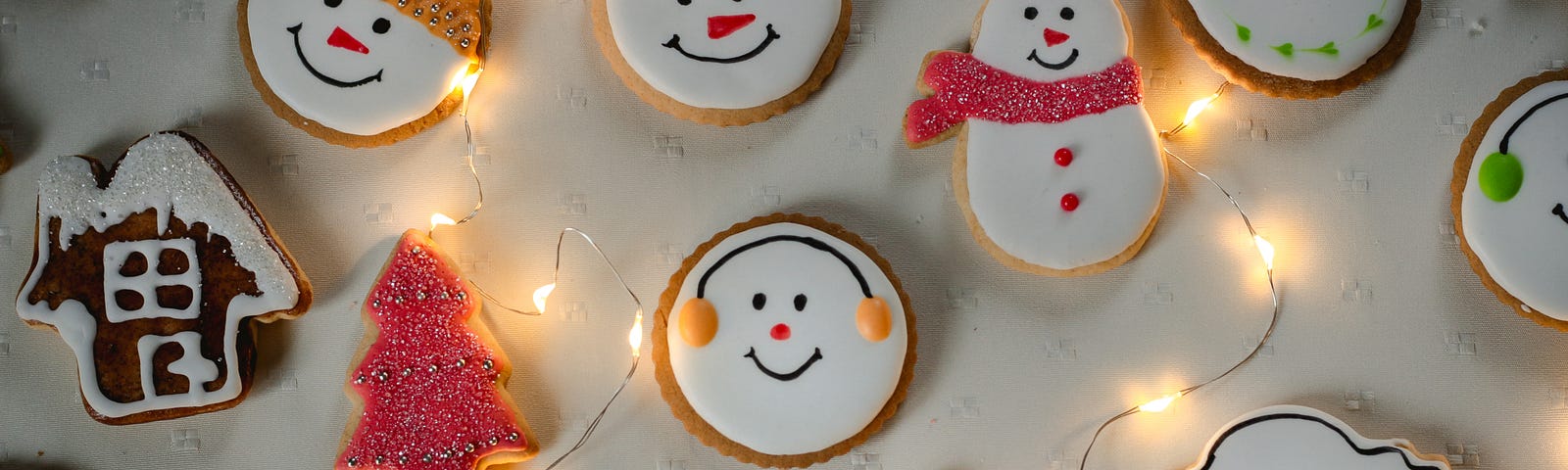 Decorated Christmas cookies on a white table with lights.