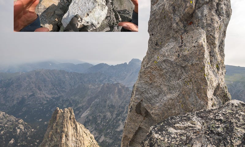 A towering granite boulder with an inset showing the feet and hands of a climber.