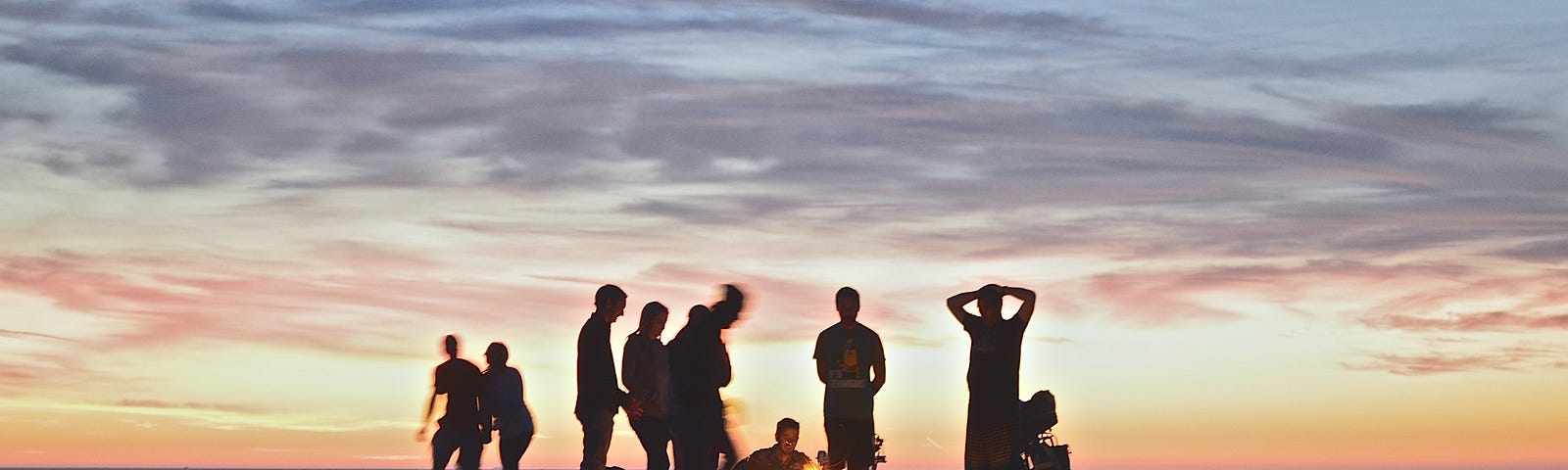 friends gathered together on the beach when the sun sets