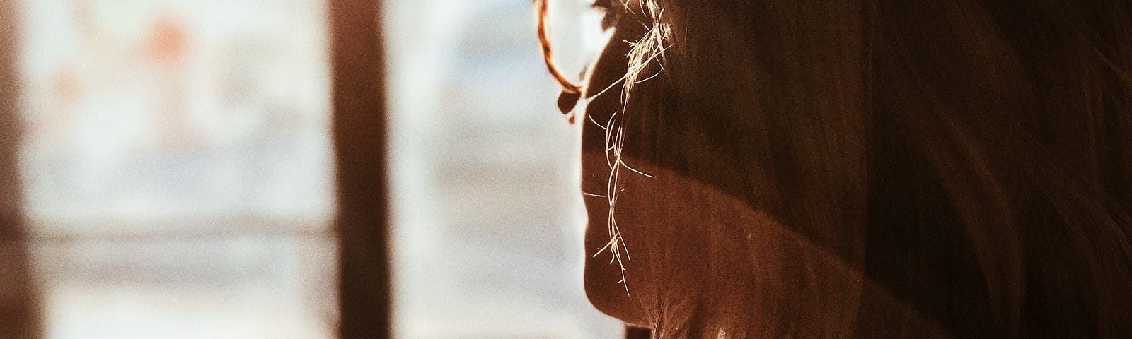 Woman wearing glasses looking out window.