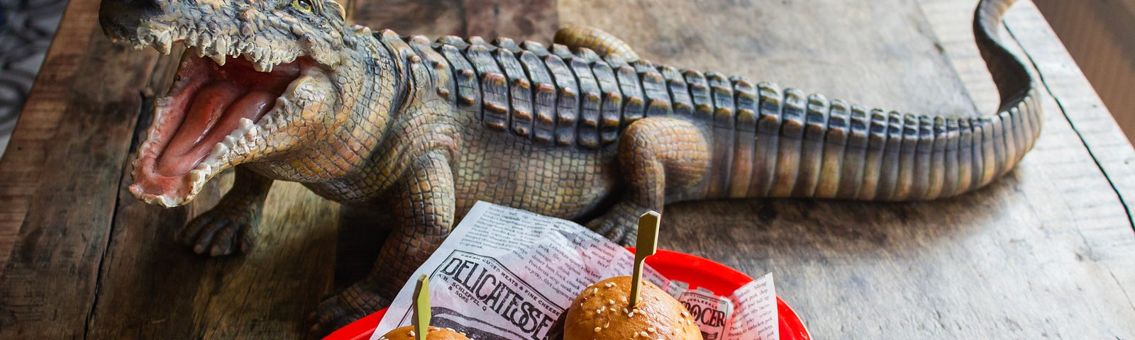 crocodile hovering around two burgers in a plastic serving dish