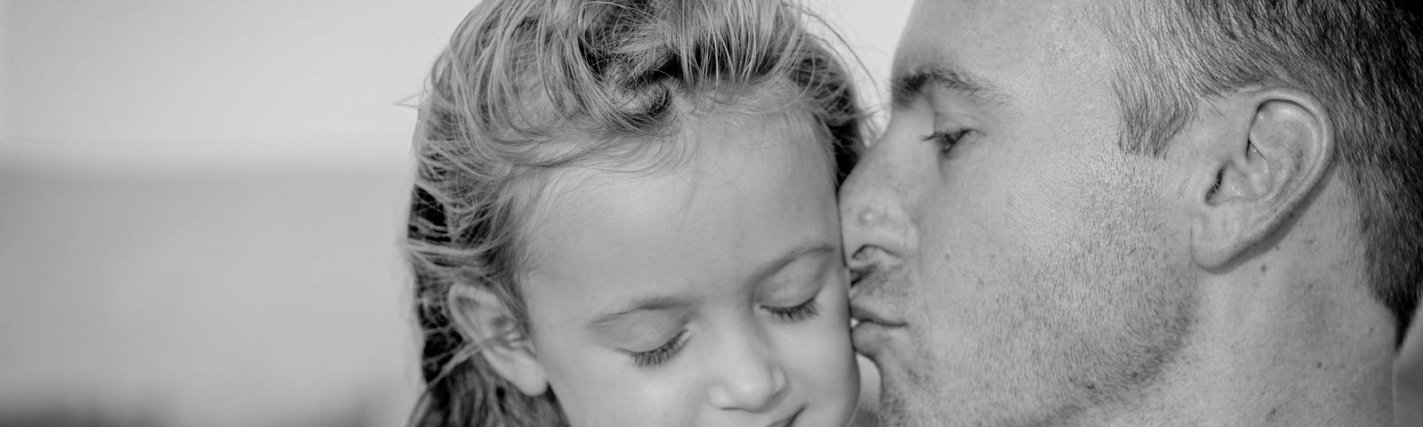 father kissing young daughter on her cheek