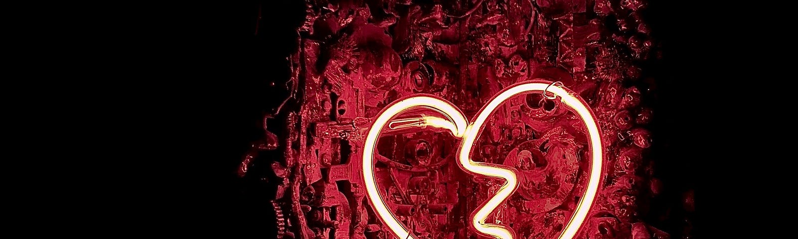 A red neon image of a heart with a crack in the middle.