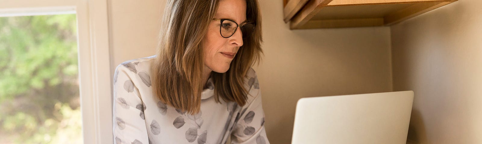 A mature woman stares at a computer screen.