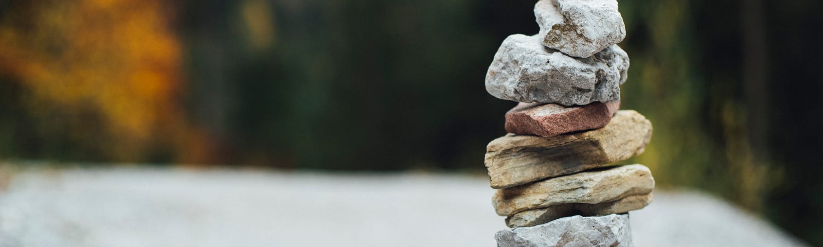 Colored stacked of balancing rocks against a distant out-of-focused background in fall’s outdoor colors.