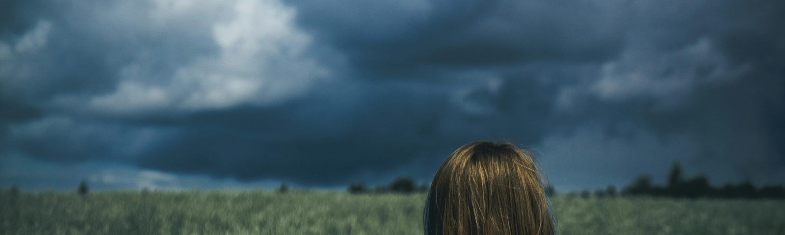 Looming of the clouds witnessed by a lady over a huge, mellow grassland.