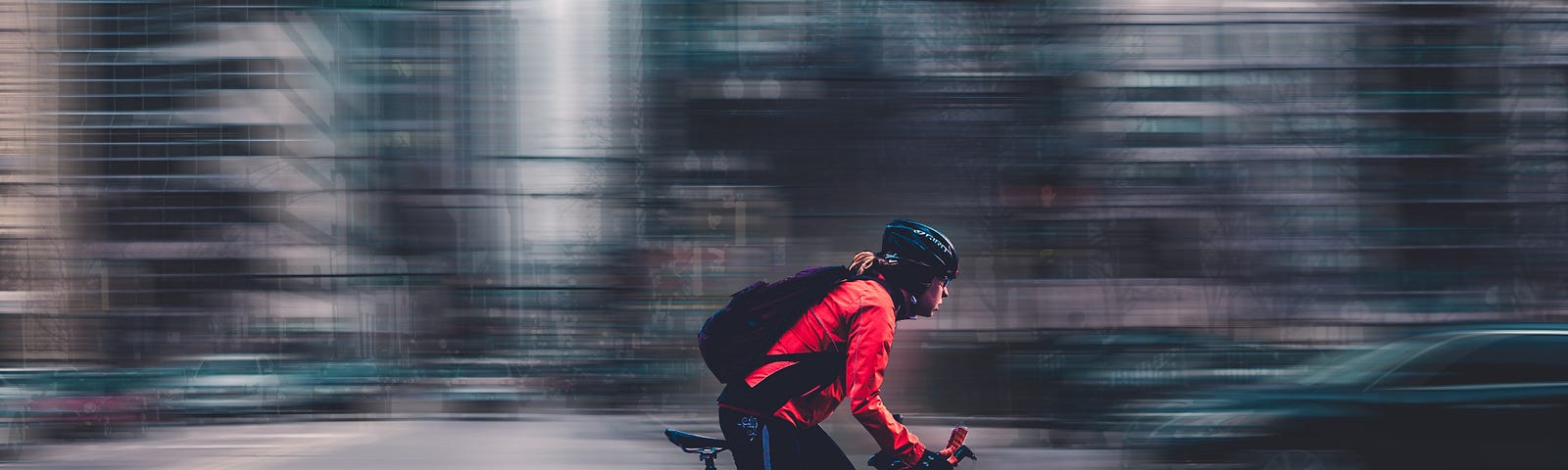 Person rides a bicycle in the city. Background blurred.