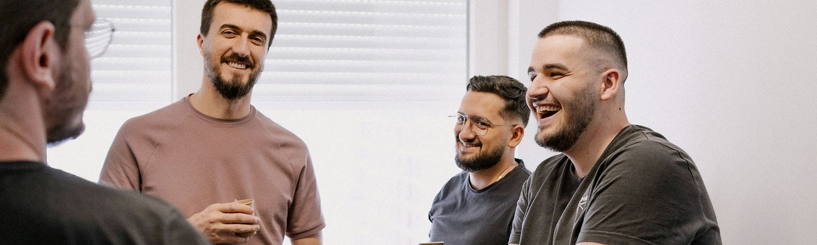 Four people standing, talking and laughing