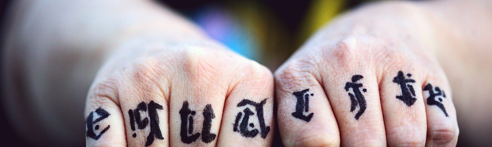 the letters of the word equality tatooed to fingers. two hands together making fists.