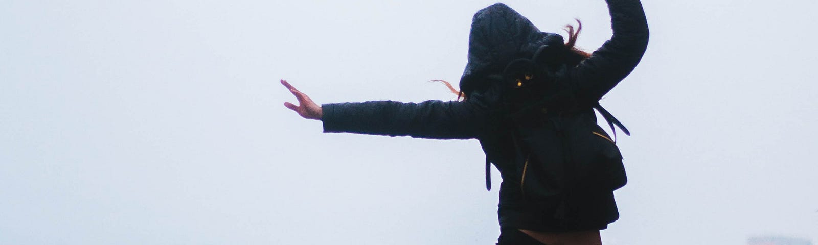 a woman, viewed from the back, jumping excitedly on a roof