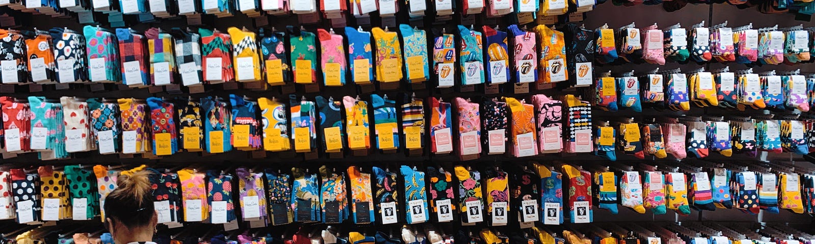 this is a photo of a person sitting on a bench in front of a display of socks.