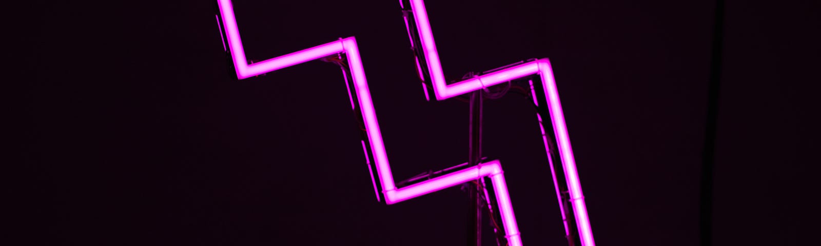 A bright pink neon sign of an arrow zigzagging down.