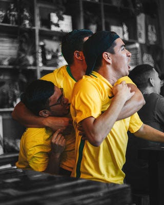 Soccer fans in yellow hugging and cheering while watching a football game