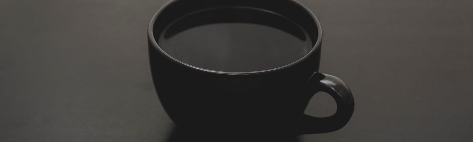 black cup of coffee sitting on a black table