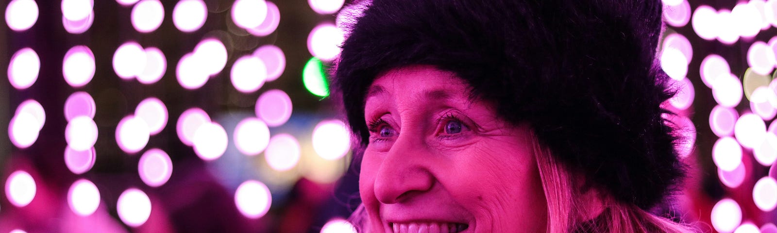 A woman brightly smiles in lights