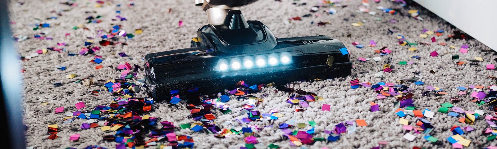 Someone is cleaning a carpet from confetti with a vacuum cleaner.