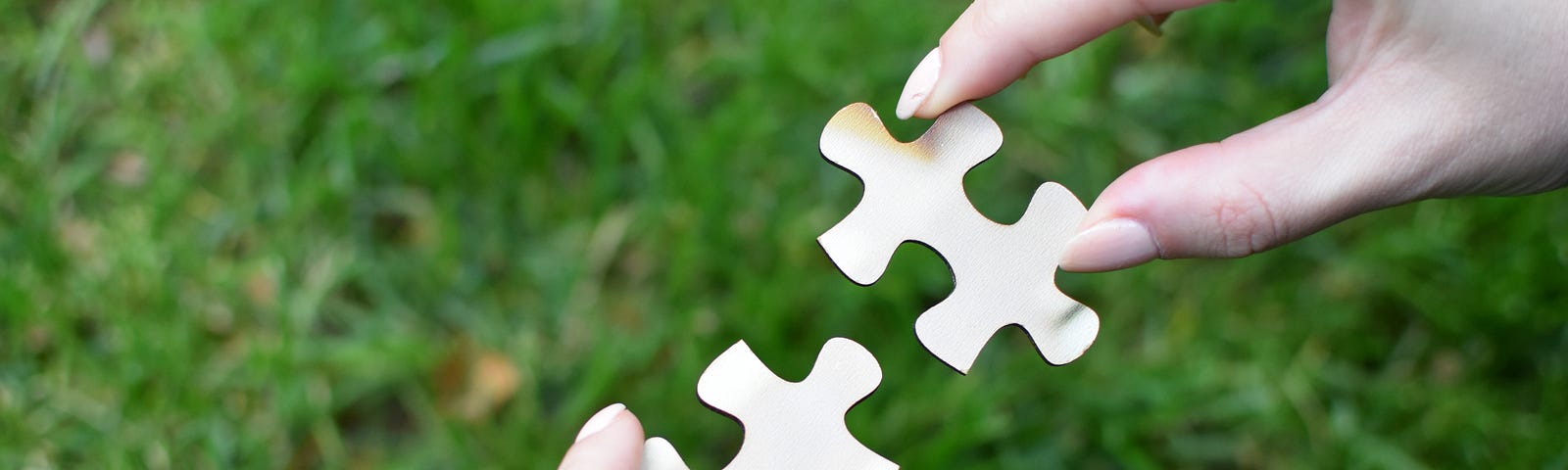 Two hands holding two puzzle pieces