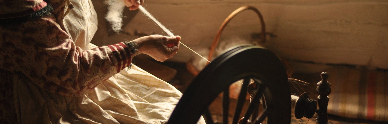 Woman spinning yarn on antique wheel