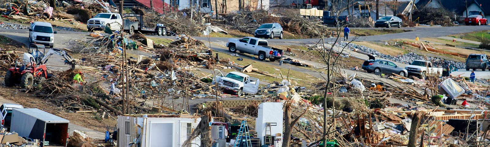 Neighborhood destroyed by tornado. Helpers working on cleanup.