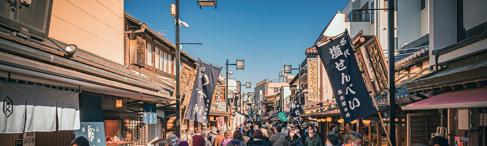 Tourists in Japan crowded on a street lined with souvenir shops and food stalls.