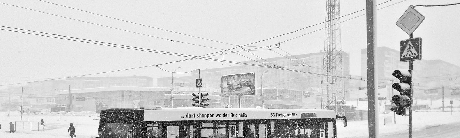 black and white photo of public bus in snowy street, with heavy clouds overhead