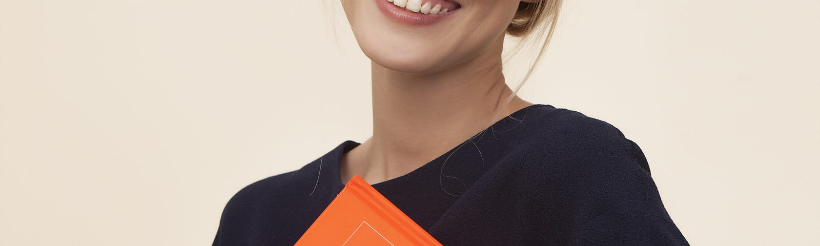 A young female teacher holding an orange portfolio.