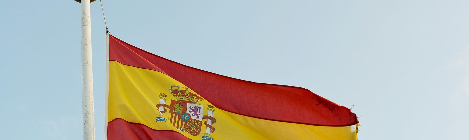 Spain’s flag fluttering on a bright sky background.