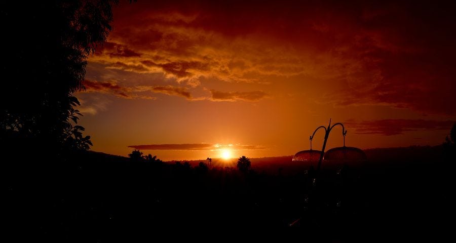 A sunset over the southern california coast with puffy clouds overhead.