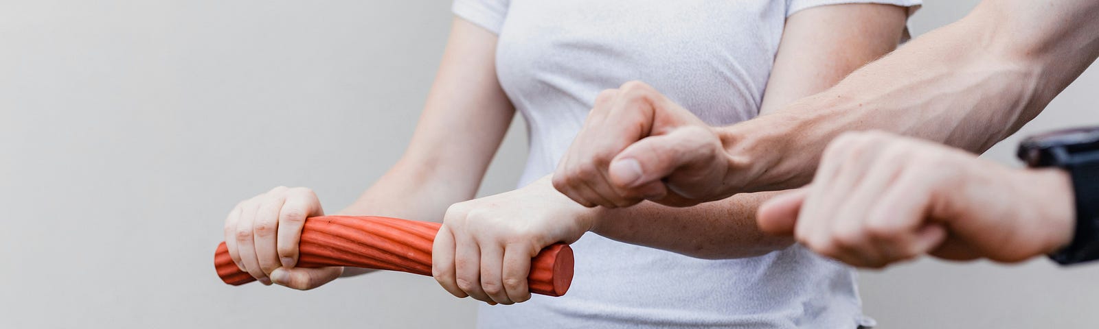 Physiotherapist teaching a patient how to do wrist and elbow mobility and strenghtening exercises using a rubber cylinder