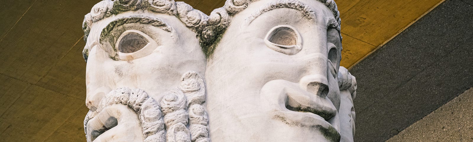 This photo shows two statue heads on a ledge.